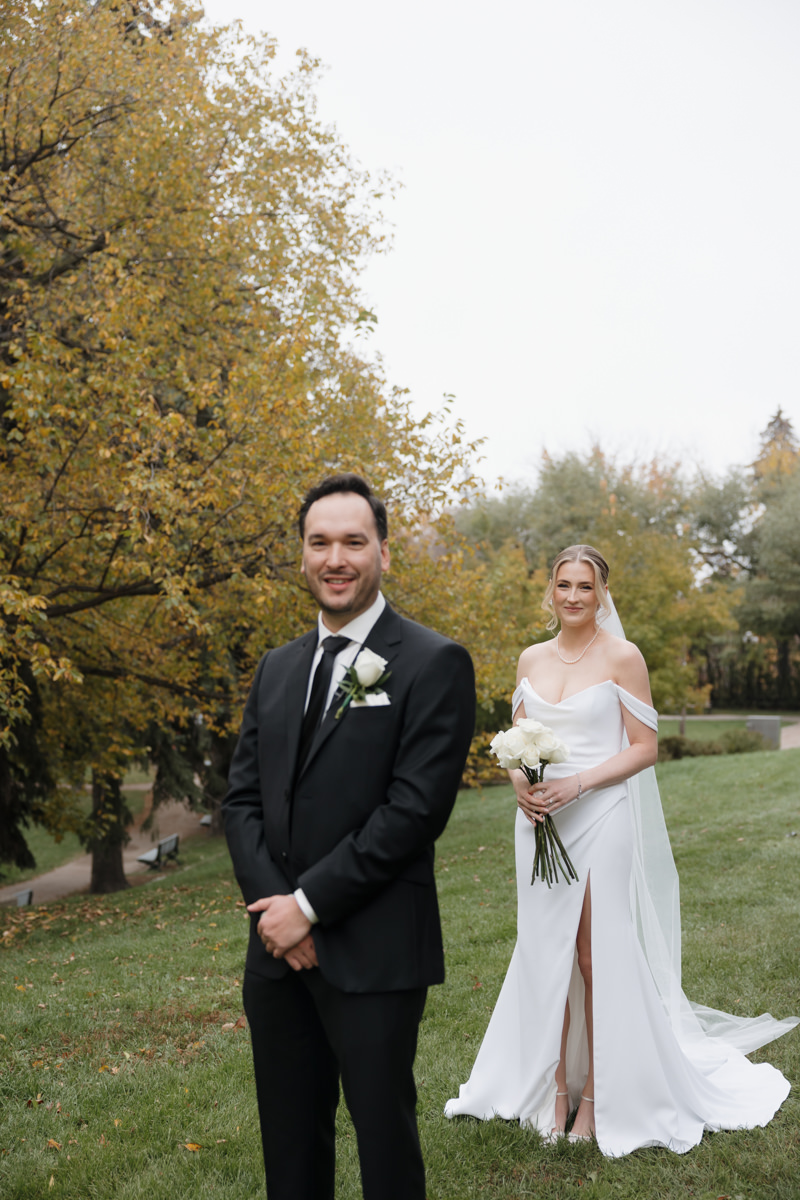 Bride and groom sharing a private first look along the South Saskatchewan River, surrounded by vibrant fall leaves for their timeless, elegant Saskatoon wedding.”
