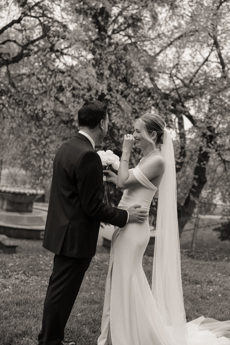 Bride and groom exchanging handwritten vows privately before their ceremony, under golden autumn leaves.