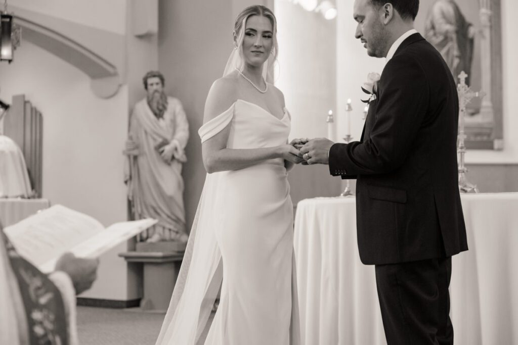 Couple holding hands at the altar during their formal church ceremony, framed by floral arrangements and soft candlelight