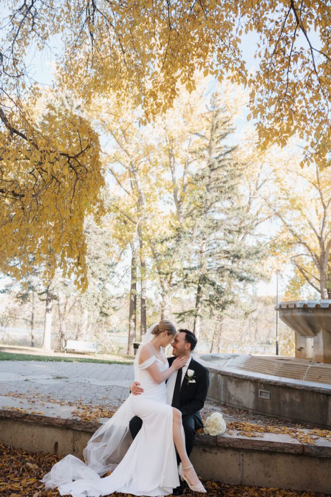 Romantic wedding portraits along Saskatoon’s scenic riverbank, with the couple framed by vibrant fall foliage.