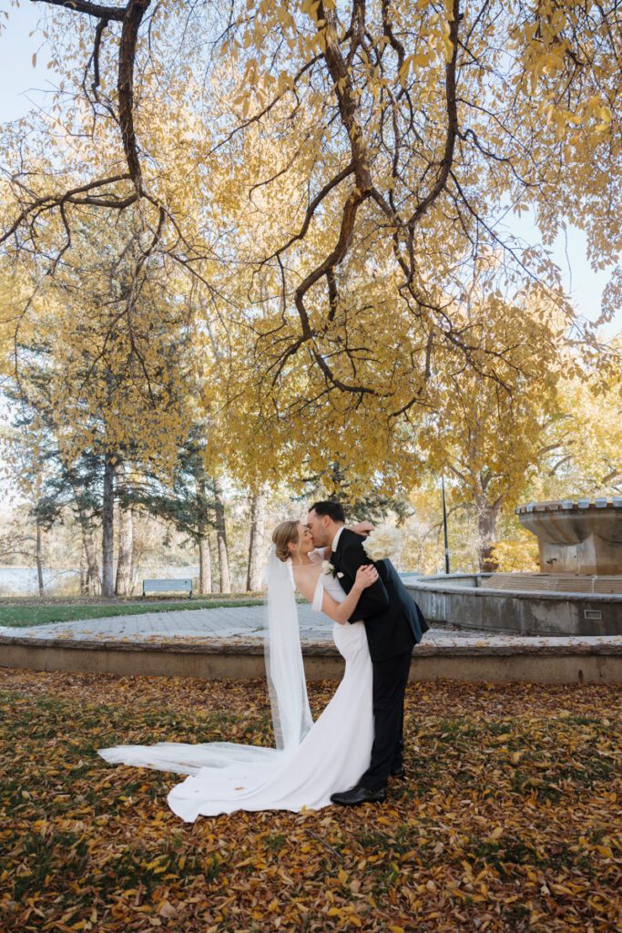 Romantic wedding portraits along Saskatoon’s scenic riverbank, with the couple framed by vibrant fall foliage.