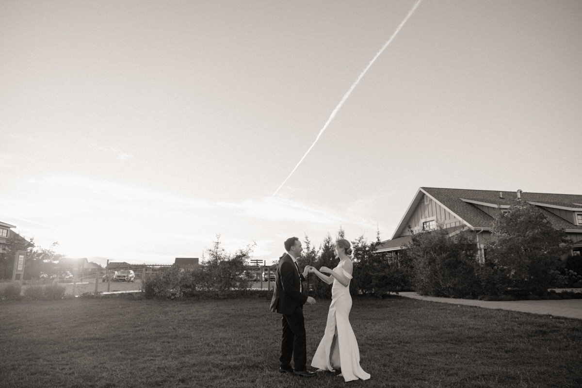 Bride twirling in her Alyssa Kristin gown as the sun sets, with her groom looking on, during a timeless wedding in Saskatchewan