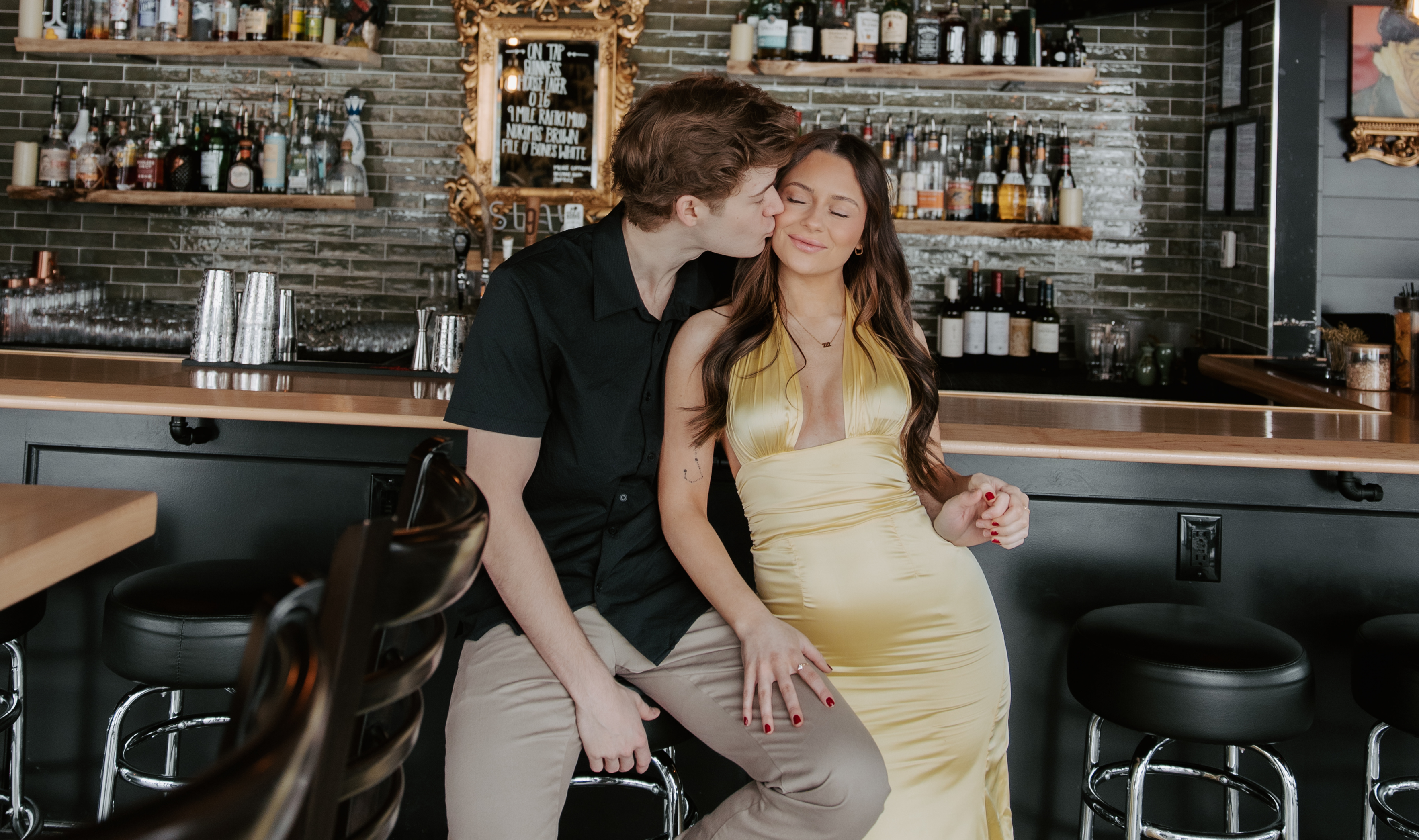 Couple sharing a kiss while standing at the entrance of Cocktail YXE