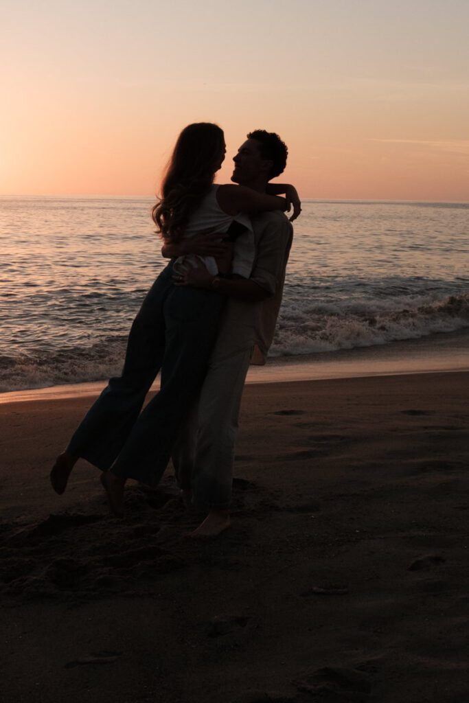 Lauren and Ben dancing on the shoreline as the sky turns golden