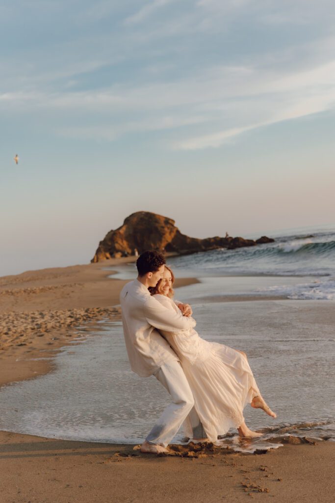 Lauren and Ben dancing on the shoreline as the sky turns golden