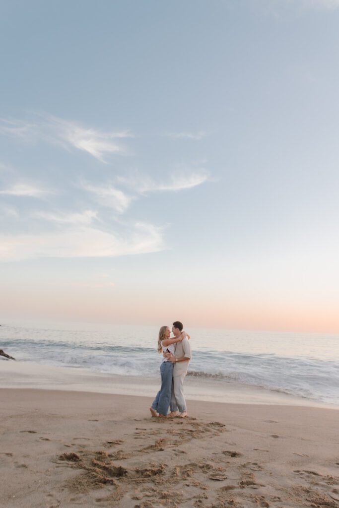 Wide shot of Laguna Beach with the ocean, cliffs, and a glowing sky