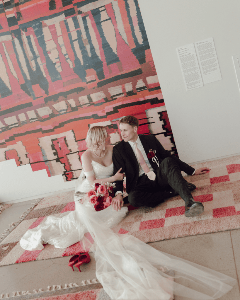 Groom in classic suit smiling at bride in gallery setting at their remai modern wedding