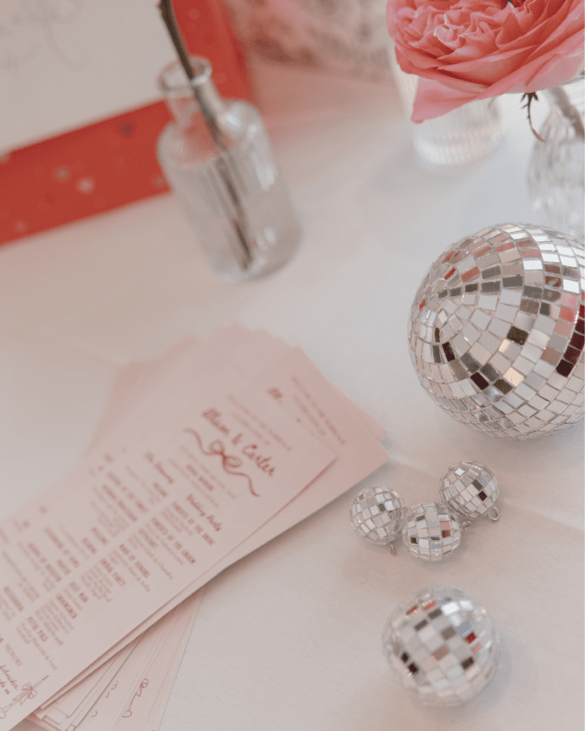Valentine’s-inspired wedding table with custom matchboxes, disco balls, and pink floral centerpieces.