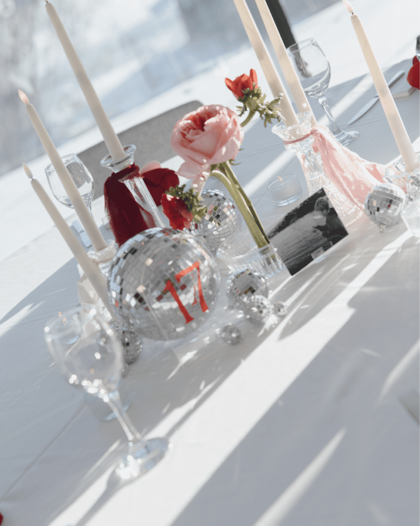 Valentine’s-inspired wedding table with custom matchboxes, disco balls, and pink floral centerpieces.