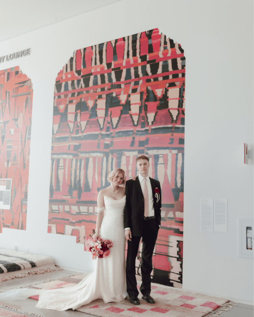 Groom in classic suit smiling at bride in remai modern gallery setting