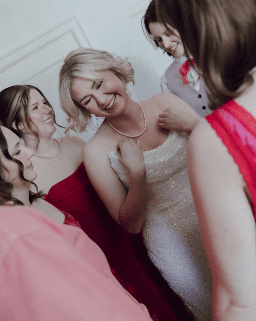 Bridesmaids laughing and adjusting their dresses under natural gallery light