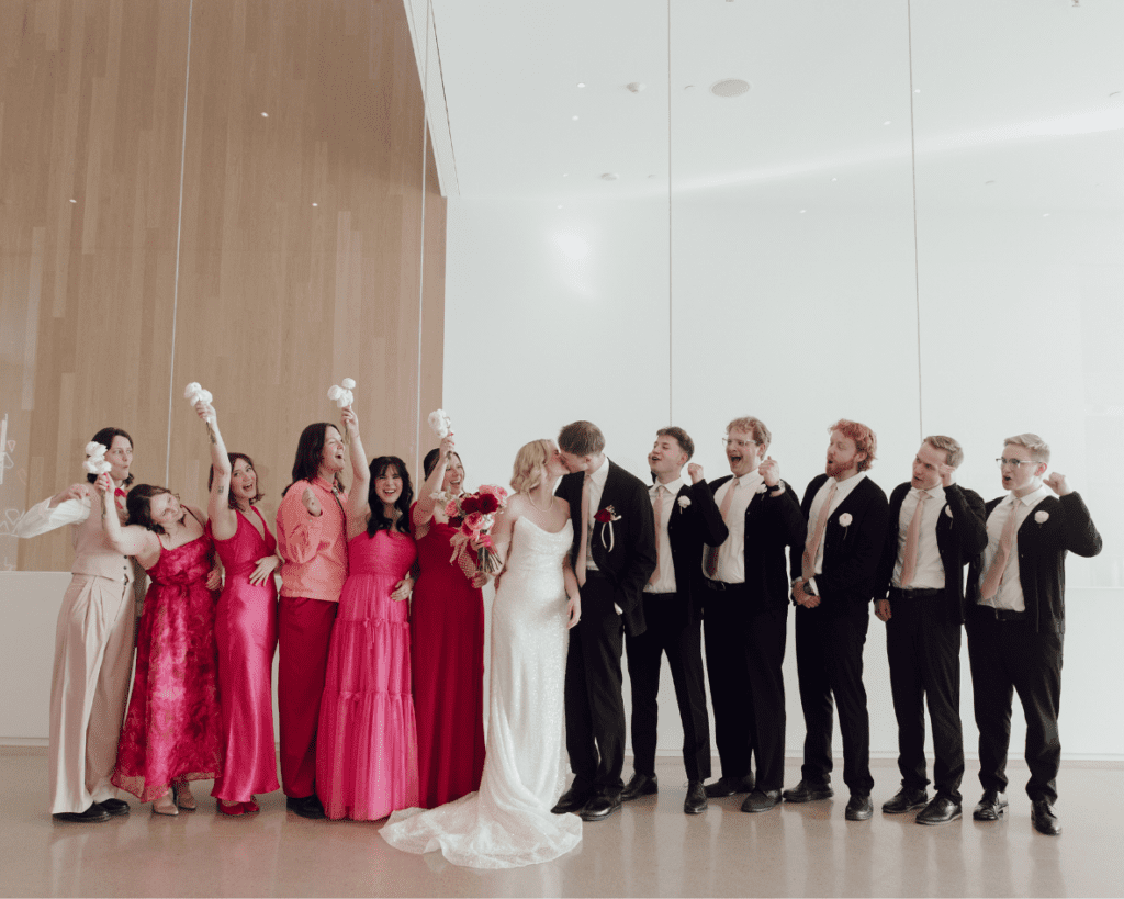 Wedding party walking through gallery space in mixed pink and red dresses