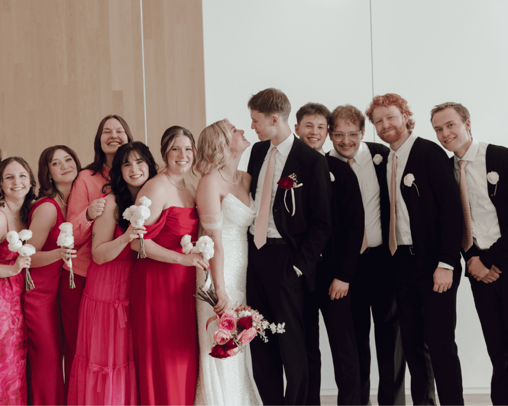 Wedding party walking through gallery space in mixed pink and red dresses