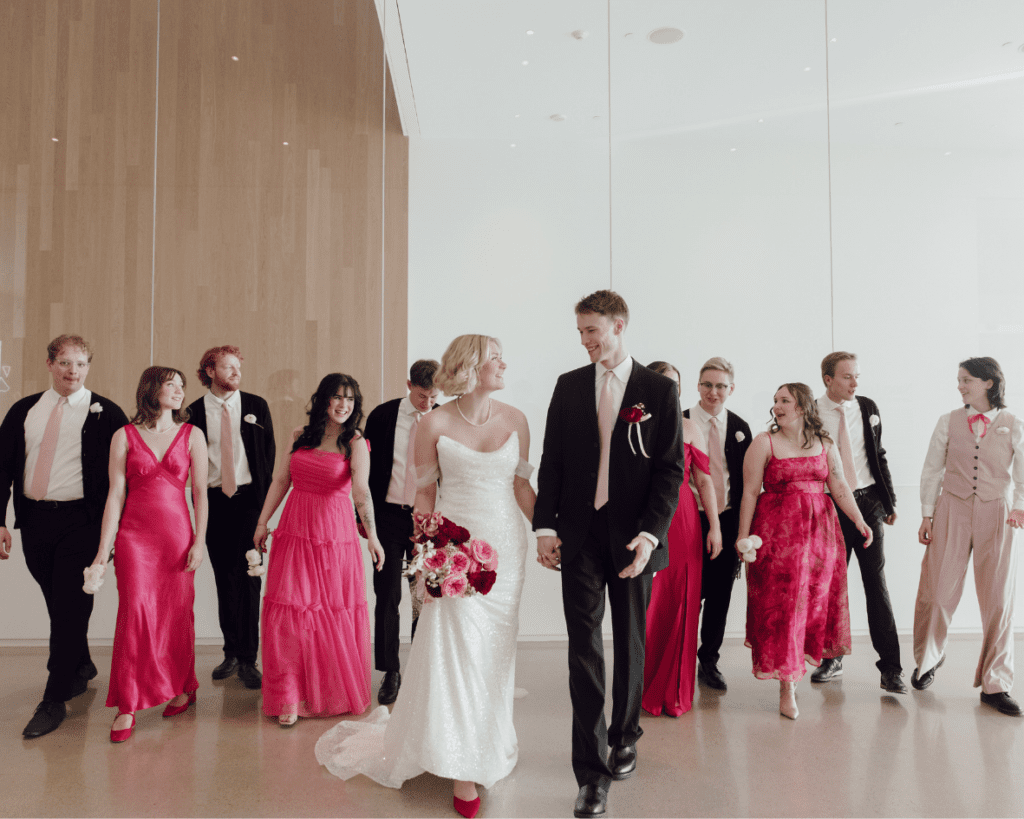 Ali and Carter posing with their wedding party in a modern gallery space filled with natural light 