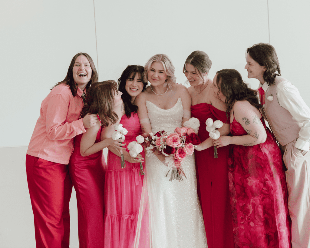 Bridesmaids laughing and adjusting their dresses under natural gallery light following their remai modern wedding