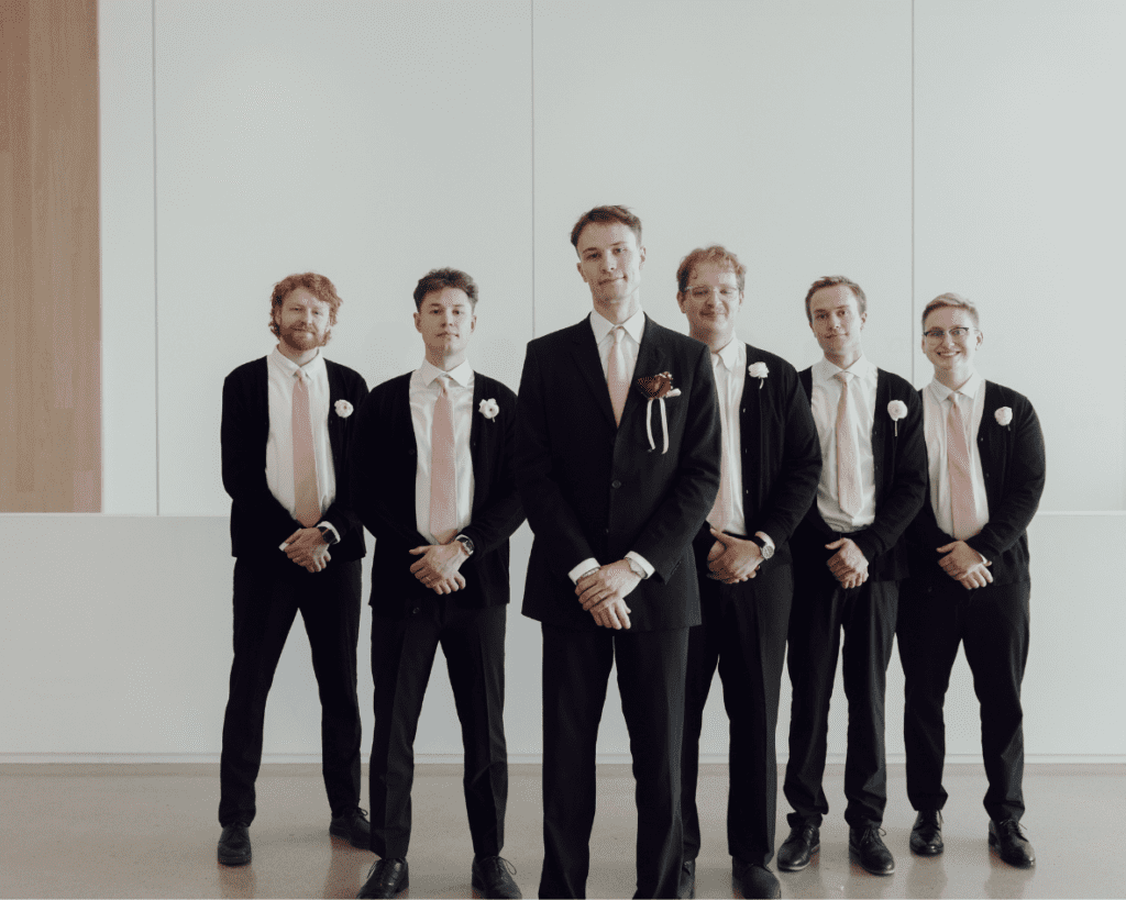 Ali and Carter posing with their wedding party in a modern gallery space filled with natural ligh