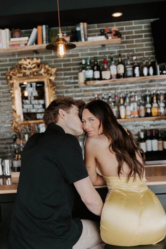 Romantic kiss between couple sitting at the bar counter under warm lighting