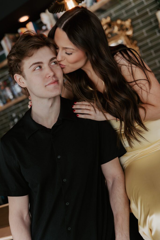 Romantic kiss between couple sitting at the bar counter under warm lighting