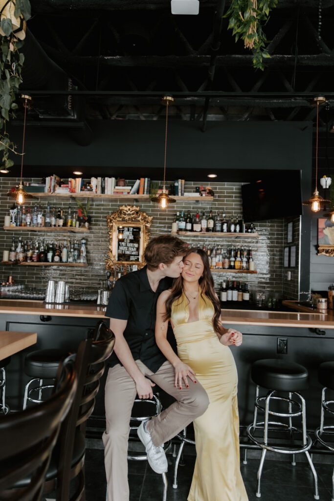 Romantic kiss between couple sitting at the bar counter under warm lighting
