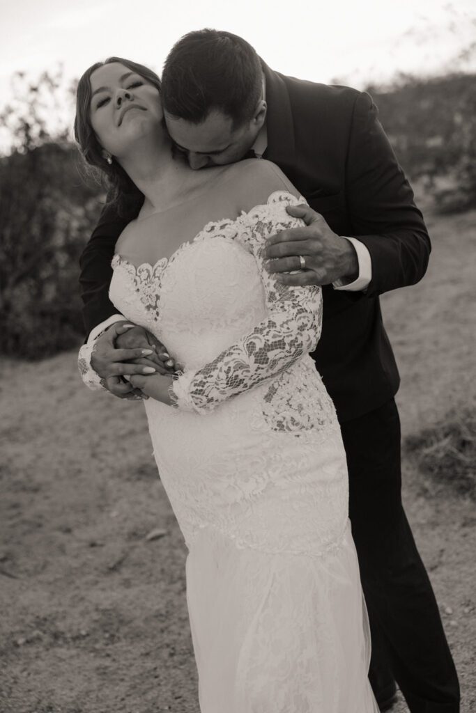 Groom holding bride’s hand as they walk through desert trails after ceremony