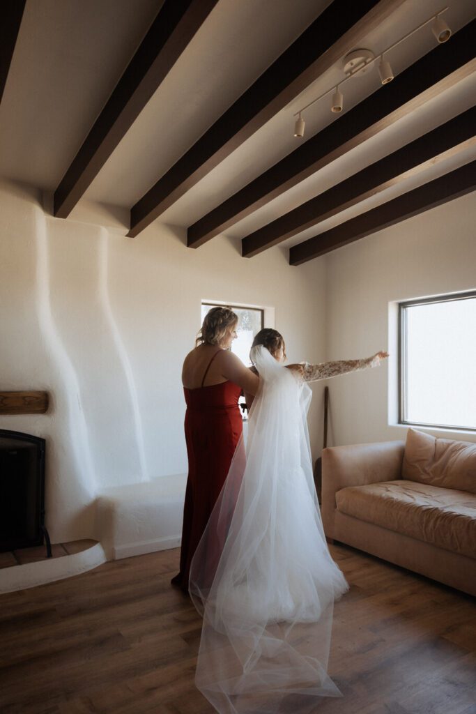 Bride zipping up wedding dress inside boho-style Joshua Tree Airbnb