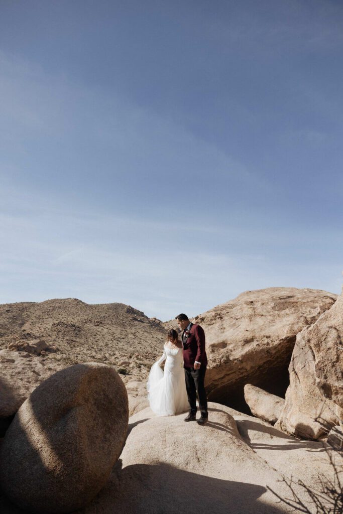 Groom holding bride’s hand as they walk through desert trails after ceremony