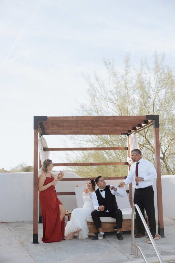 Bride and groom laughing during champagne spray celebration by the pool