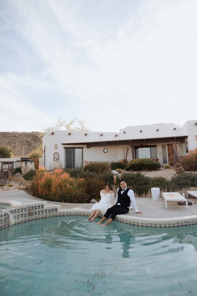 Bride and groom laughing during champagne spray celebration by the pool