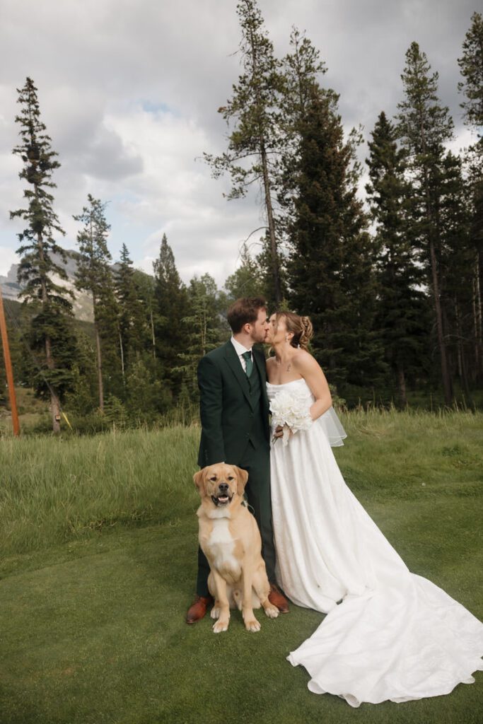 Newlyweds sharing a kiss under cloudy skies in the Canadian Rockies