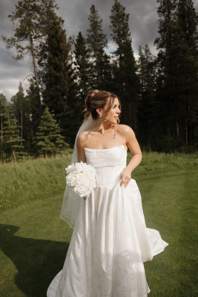 Bride in elegant gown with veil flowing in the Canmore wind