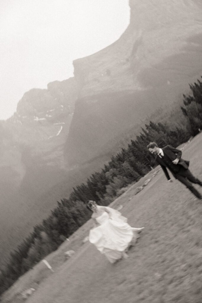 Couple holding hands, running through the rain at Canmore wedding venue
