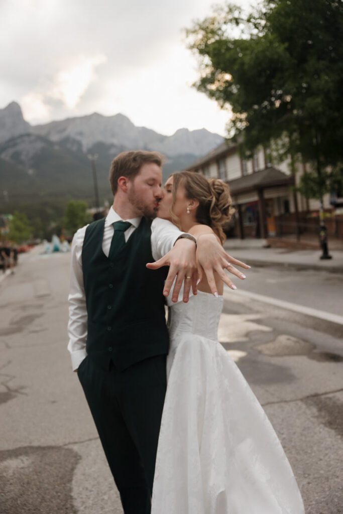 Newlyweds sharing a kiss under cloudy skies in the Canadian Rockies