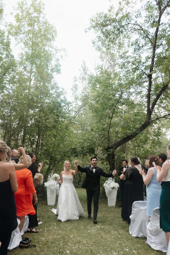 Newlyweds walking down the aisle hand in hand with huge smiles in moon lake wedding photography