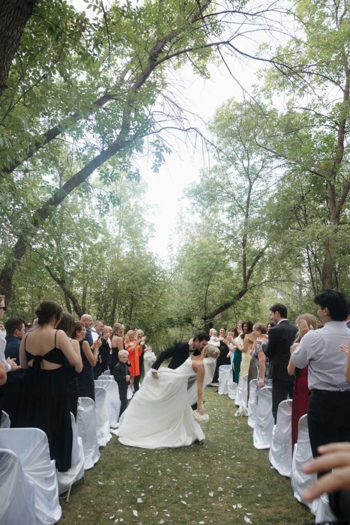 Newlyweds walking down the aisle hand in hand with huge smiles in moon lake wedding photography