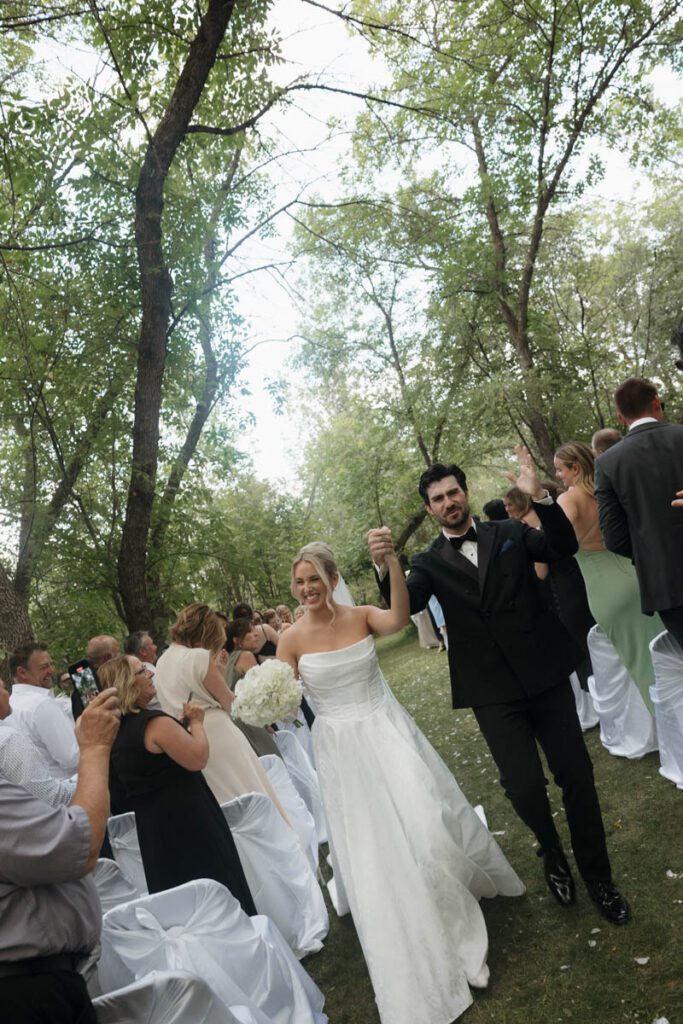 Newlyweds walking down the aisle hand in hand with huge smiles