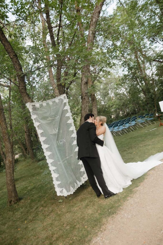 Couple kissing in front of their welcome sign in their moon lake wedding photography