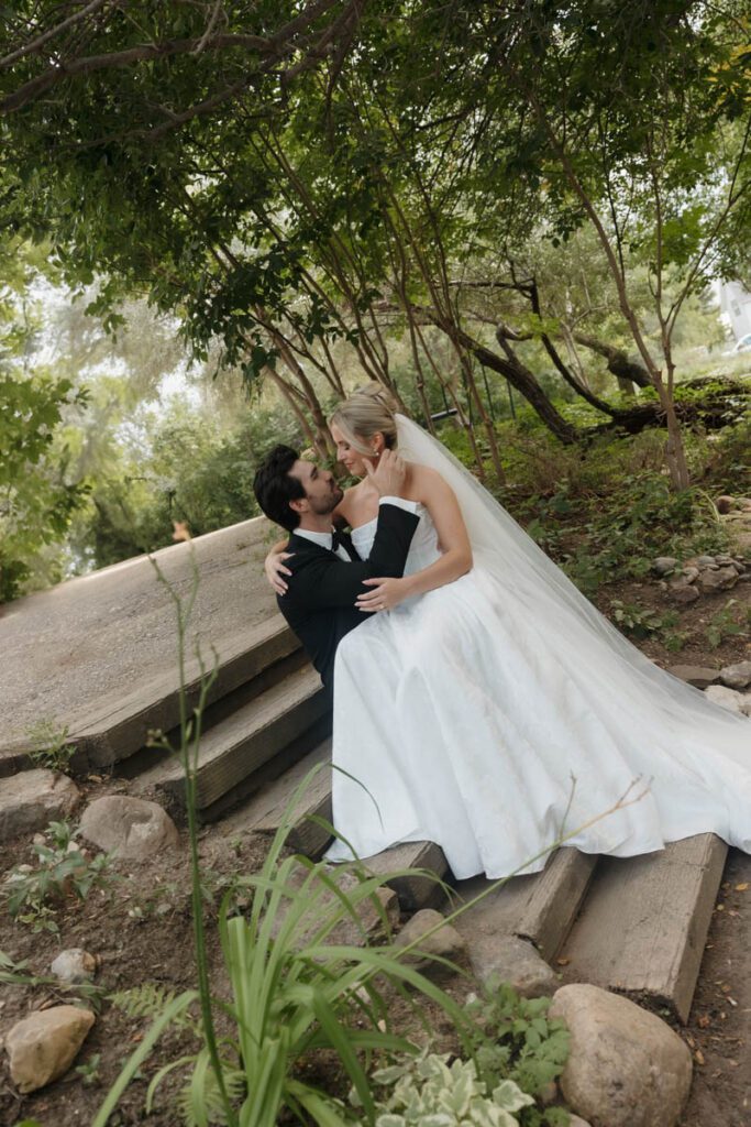 Tender kiss shared under a canopy of trees with dappled light in moon lake wedding photography