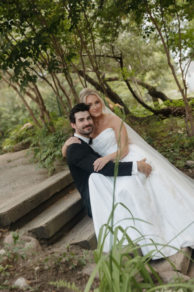 Tender kiss shared under a canopy of trees with dappled light in moon lake wedding photography
