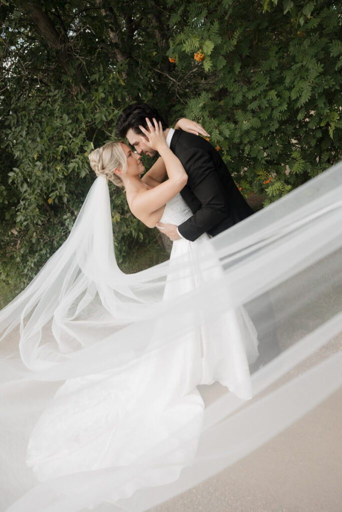 Veil floating in the wind behind the couple during their moon lake wedding photography sunset portraits