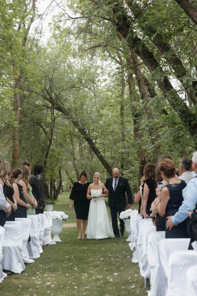 Bride walking down the aisle with her father, veil flowing in the breeze in moon lake wedding photography