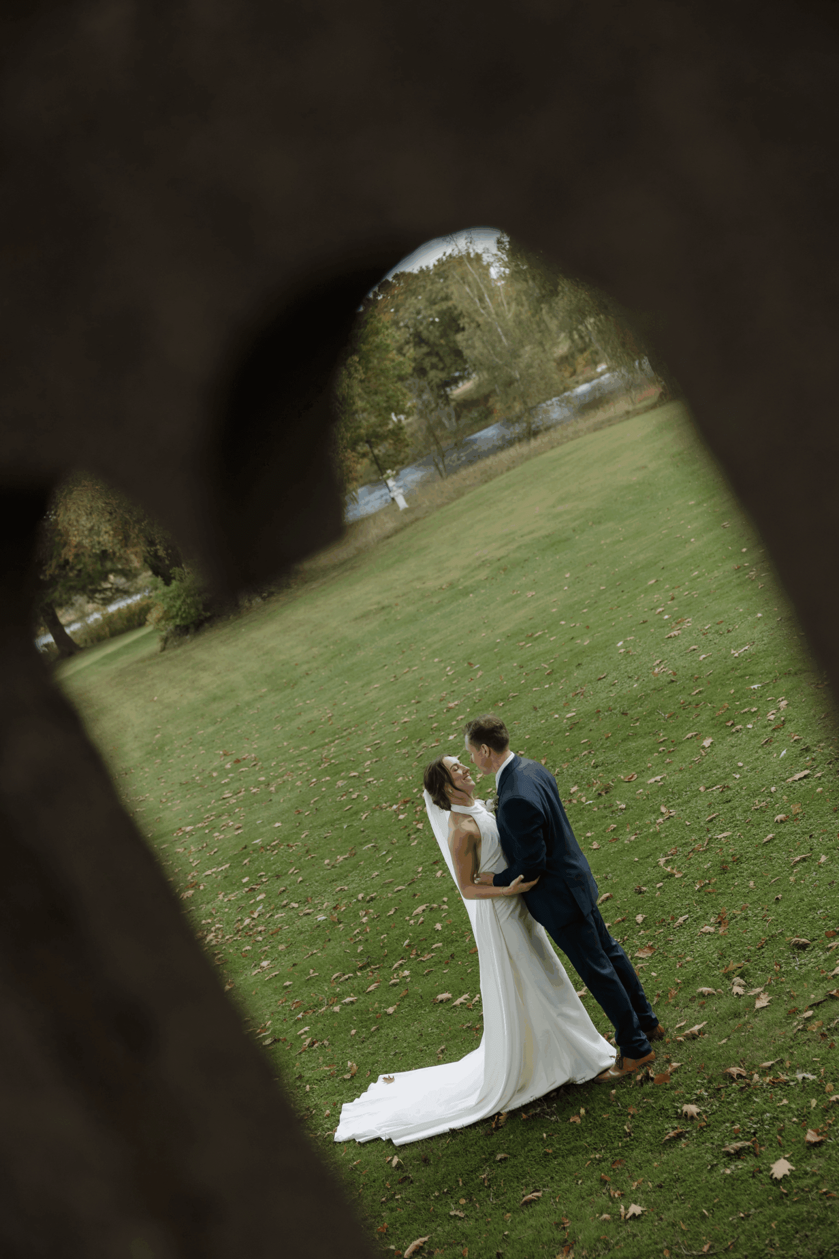 Bride and groom walking hand in hand through a scenic courtyard.