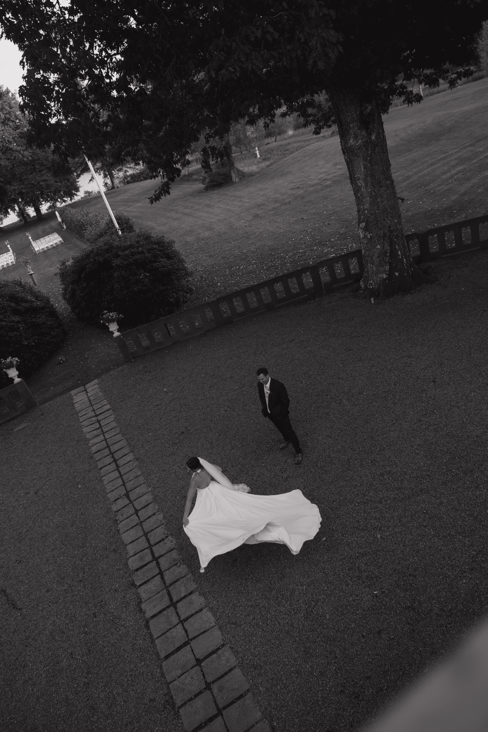 Bride and groom walking hand in hand through a scenic courtyard.